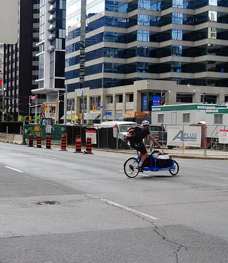 A cargo bicycle crossing a city street.