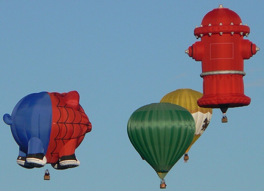 Four hot air balloons in the sky over New Mexico in 2012, including one shaped like a fire hydrant.