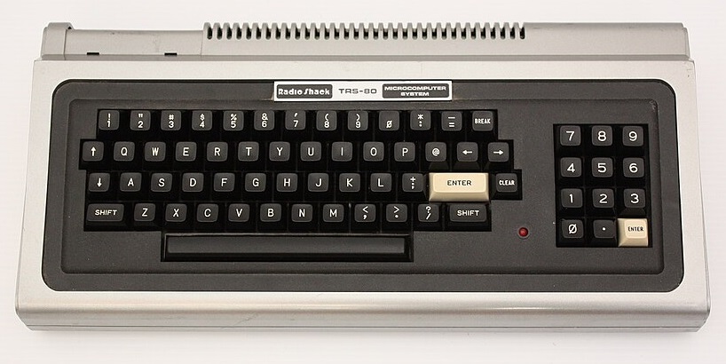 A typewriter-style TRS-80 keyboard with a red indicator light and Radio Shack logo.